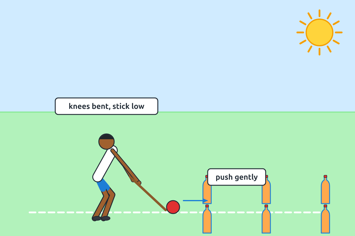 A child pushing a ball with a stick between cones