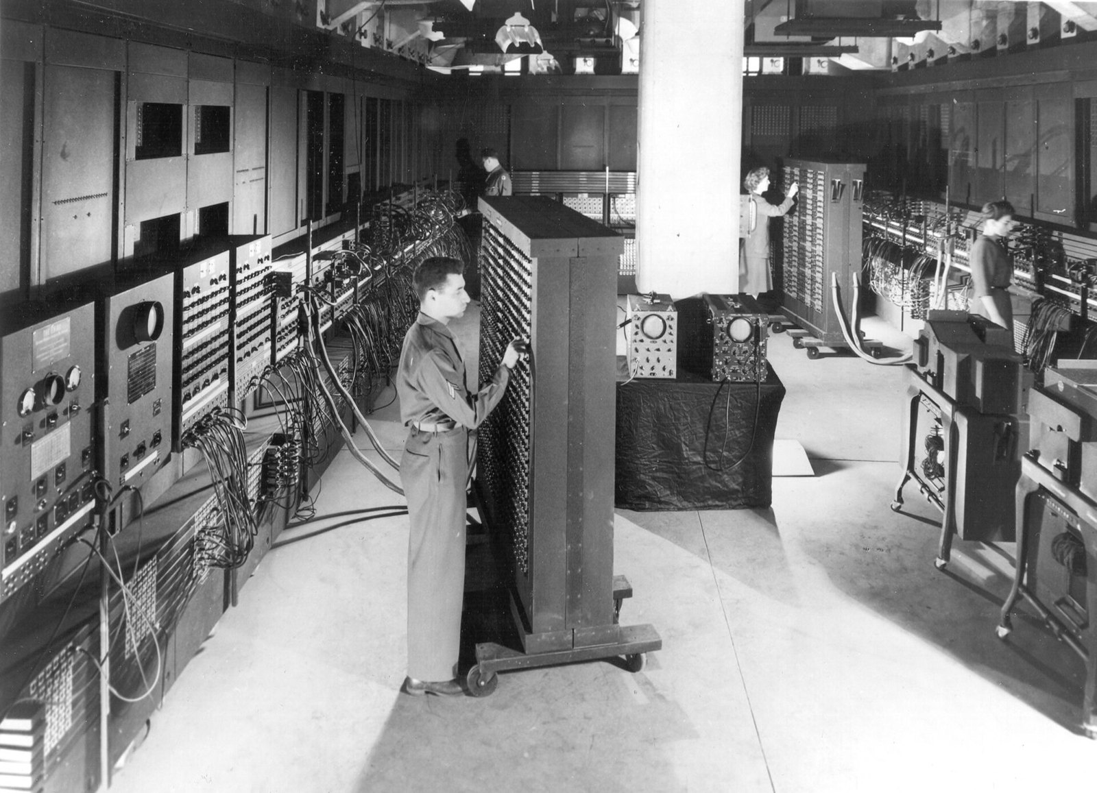 The ENIAC computer filling a large room, with people operating it