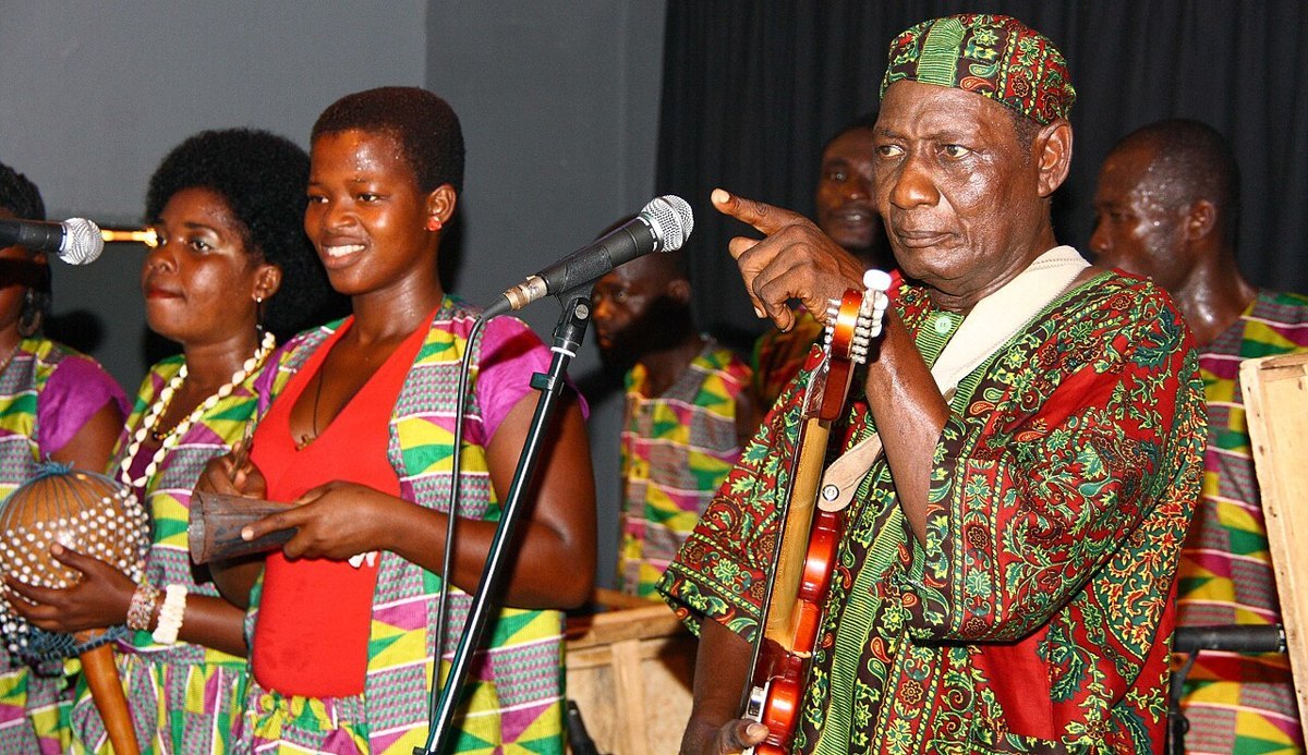A highlife band with guitars, trumpets and drums performing