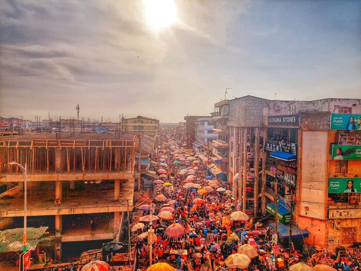 A crowded Ghanaian market with colourful cloth and traders