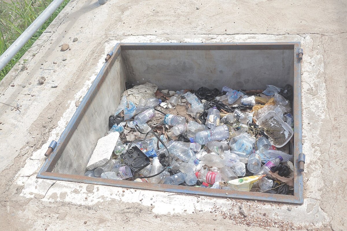 A gutter blocked with plastic waste and stagnant water