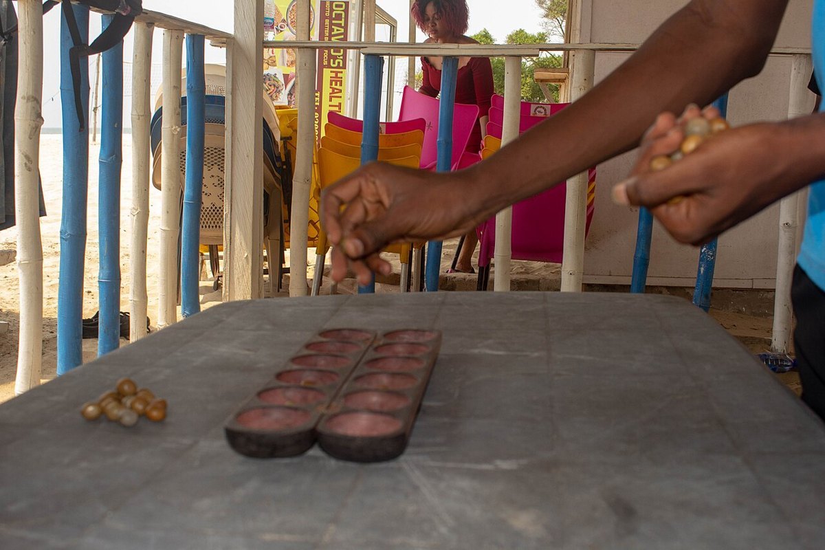 Two children playing oware on a carved wooden board